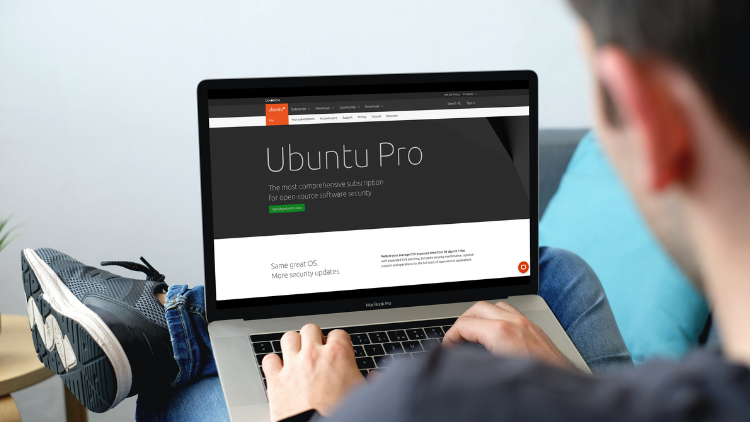 Ein Mann, der sich die Ubuntu Pro Webseite auf seinem Laptop ansieht - Das Ubuntu Pro Abo ist da: Was bedeutet das für uns Nutzer?